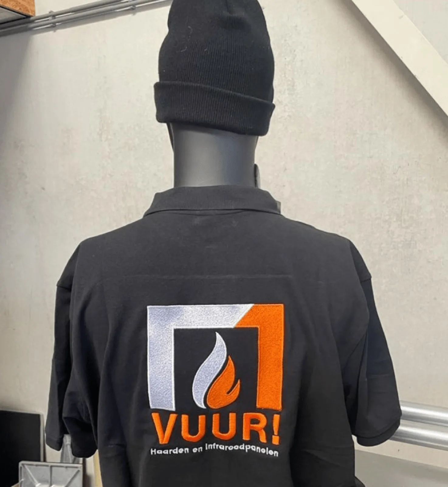 Groot geborduurd logo in wit en oranje op zwarte bedrijfskleding