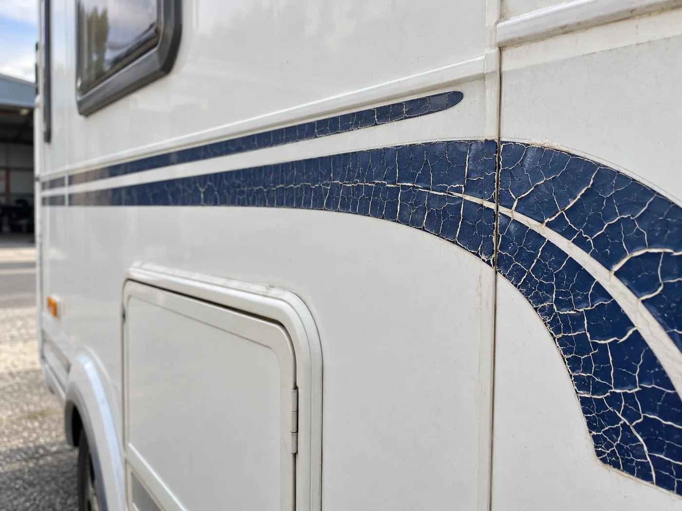 Fijn gebarsten en broze blauwe striping op een camperwand