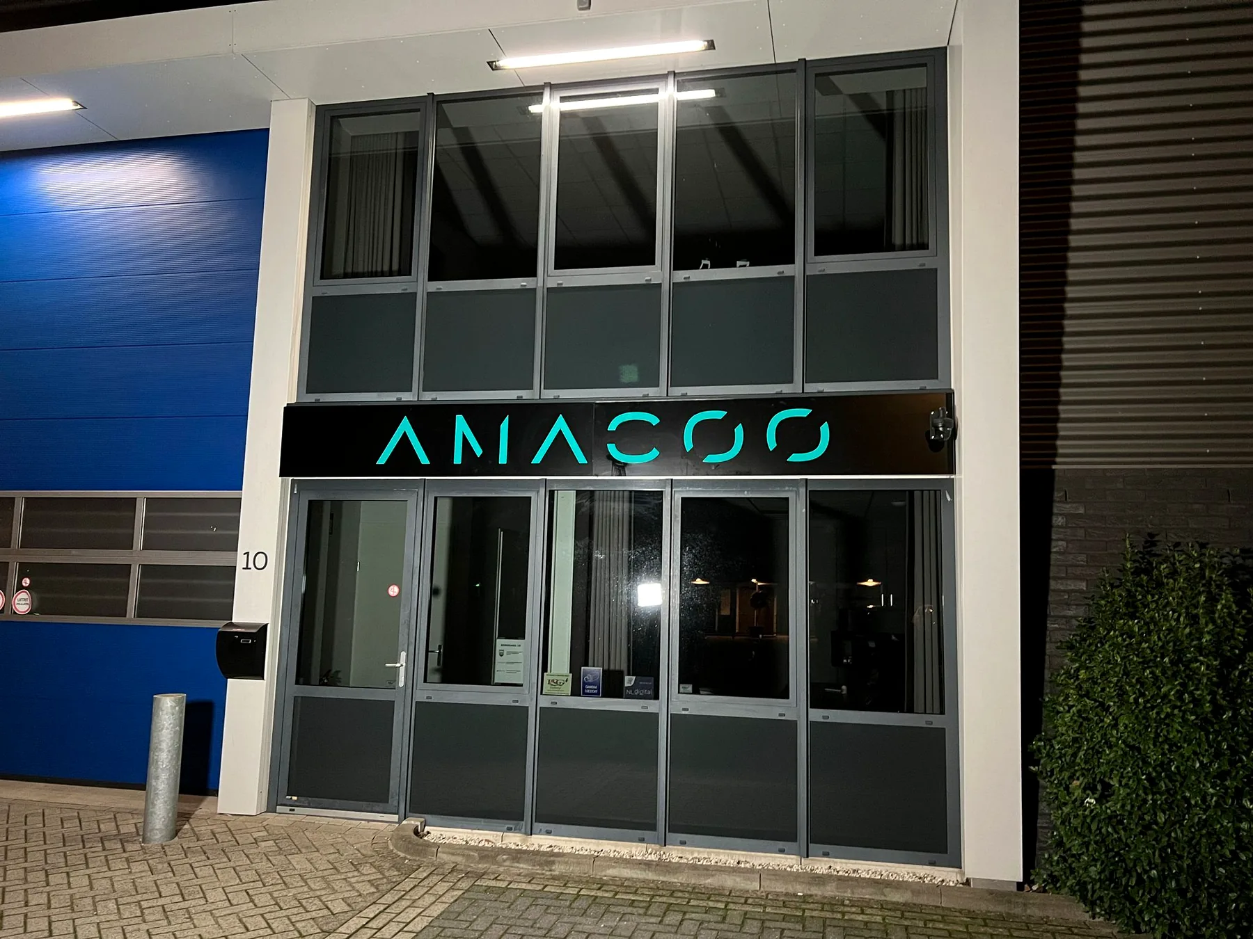 Verlichte turquoise gevelletters van Anacoo boven de entree