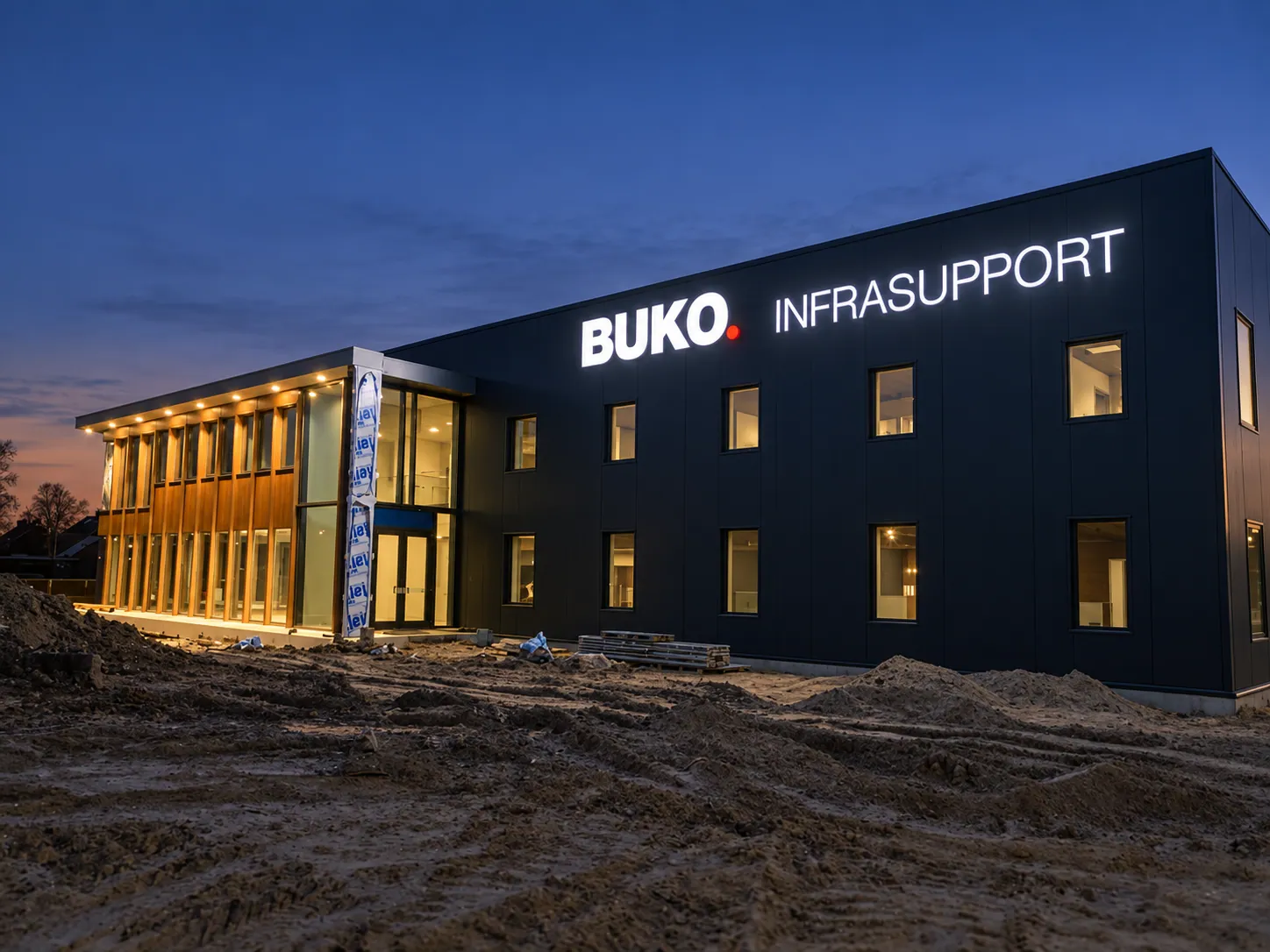 Verlichte gevelletters van BUKO Infrasupport op een donker bedrijfspand