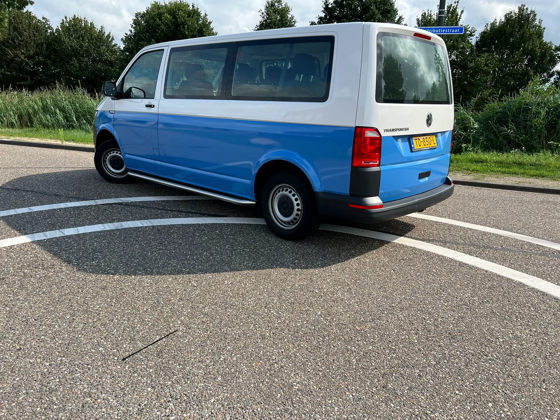 Volkswagen buscamper met blauwe deelwrap, schuin van achteren