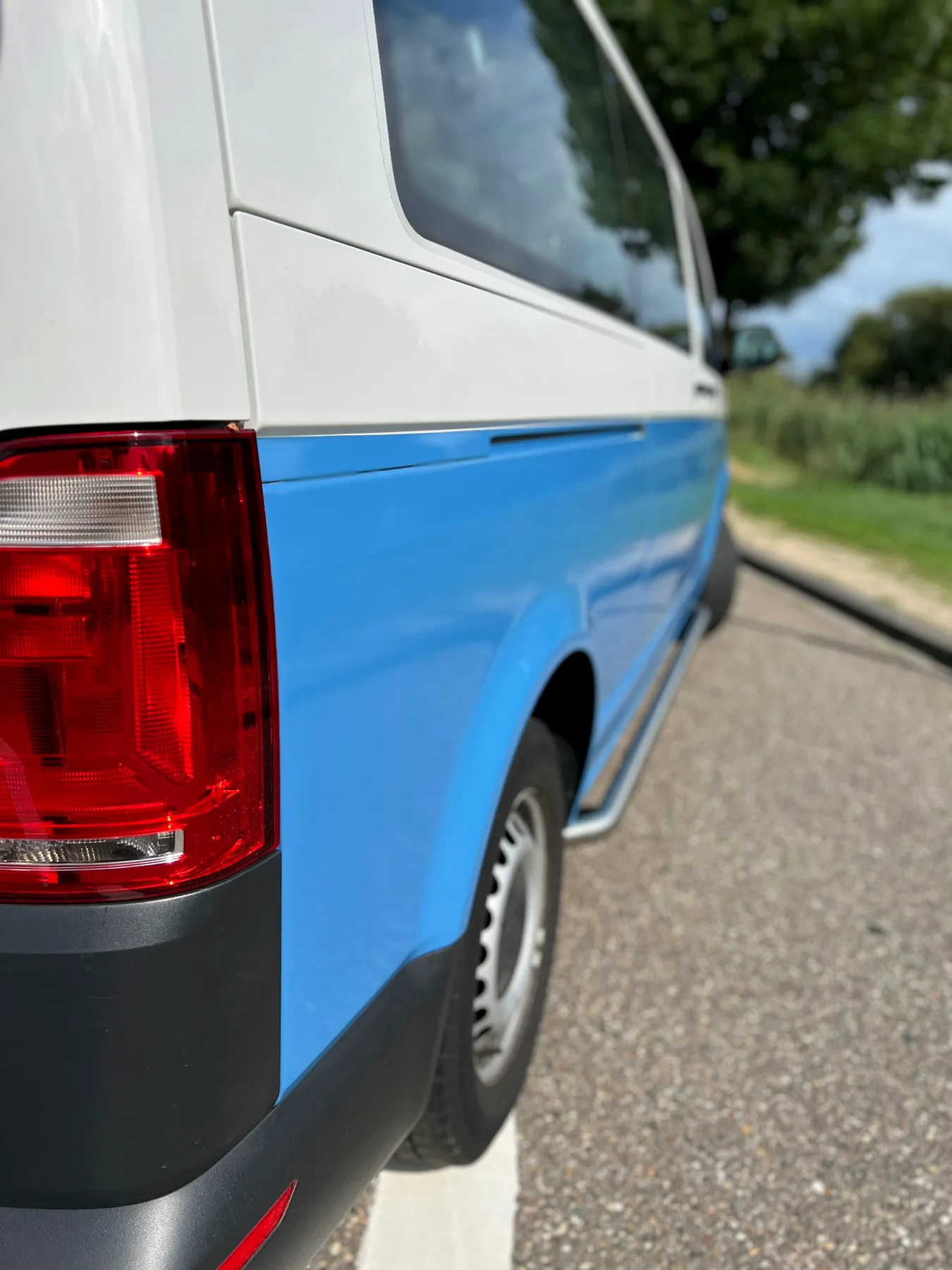 Detail van de blauwe deelwrap en achterlamp van een buscamper