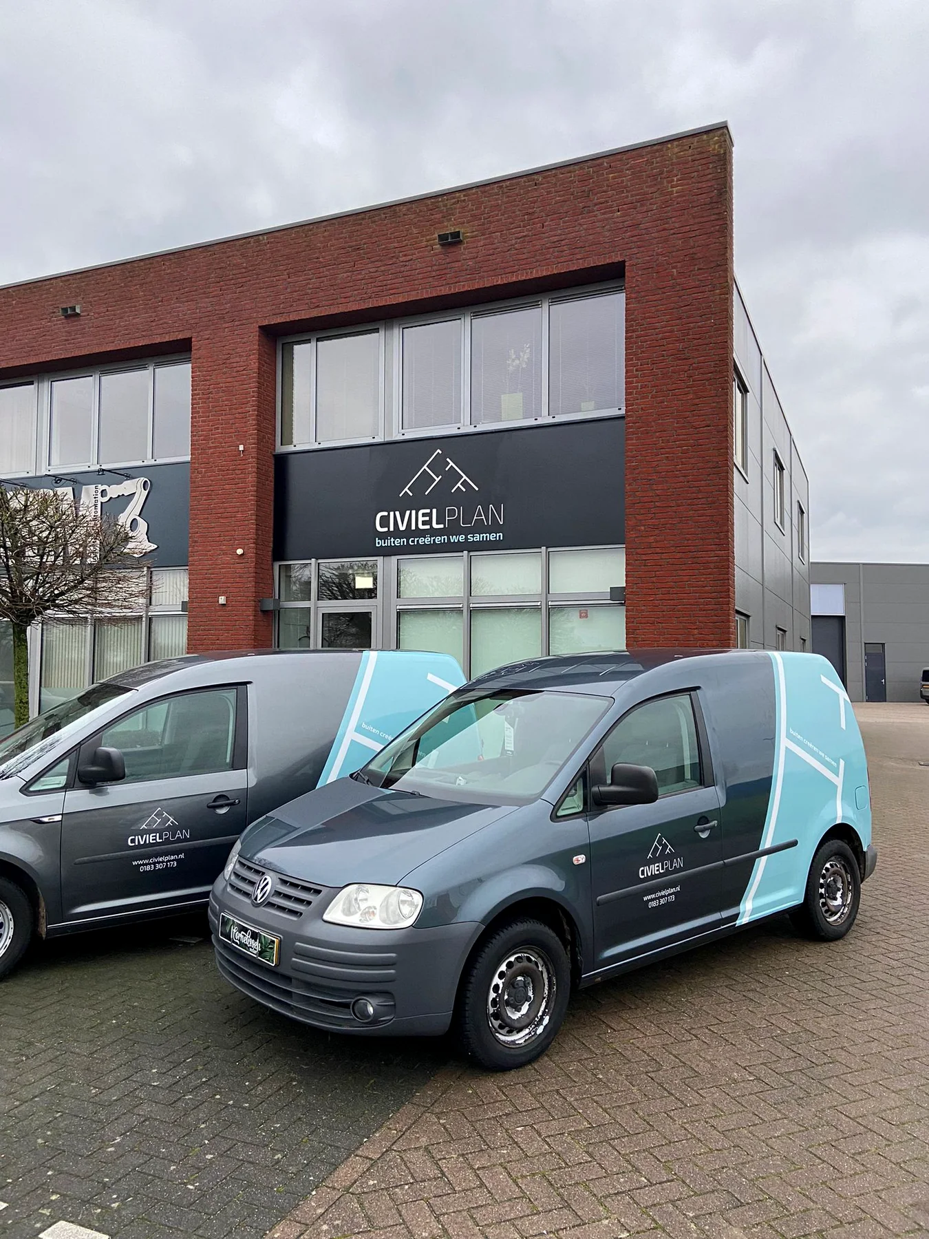 Twee beletterde Civielplan-bedrijfswagens voor de gevel met hetzelfde logo