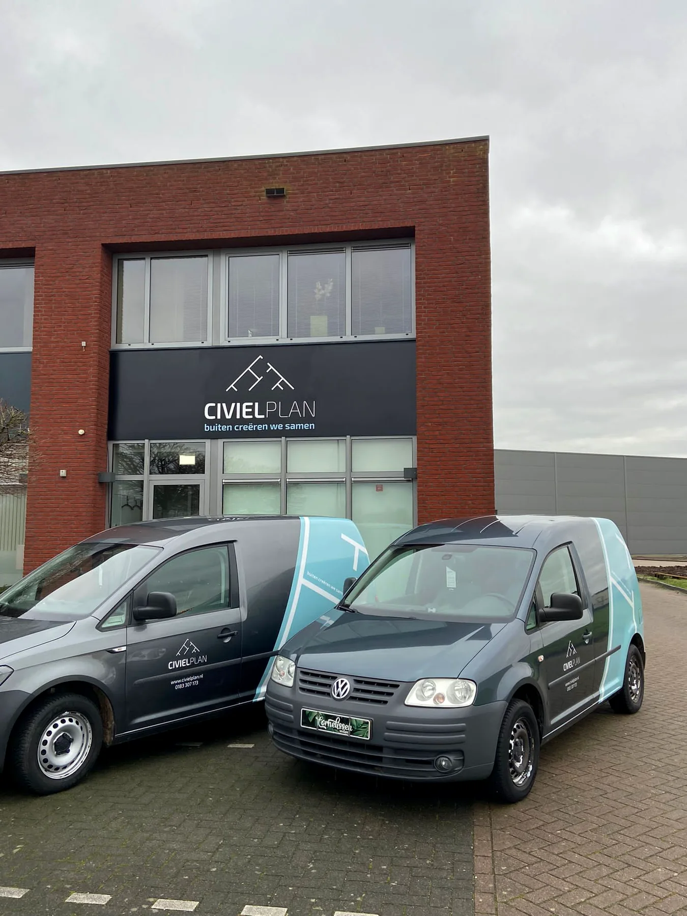 Twee Civielplan-bedrijfswagens voor de beletterde gevel van het bedrijfspand