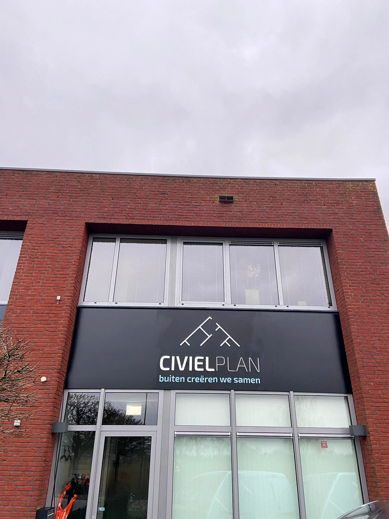 Frontale gevelbelettering van Civielplan op een antraciet gevelvlak
