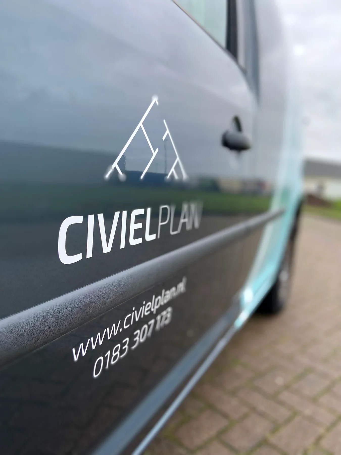 Close-up van het witte Civielplan-logo en de contactgegevens op een bedrijfswagen