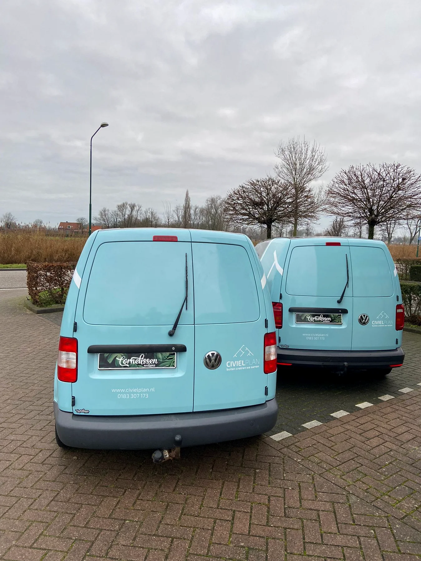 Achteraanzicht van twee lichtblauwe Civielplan-bedrijfswagens