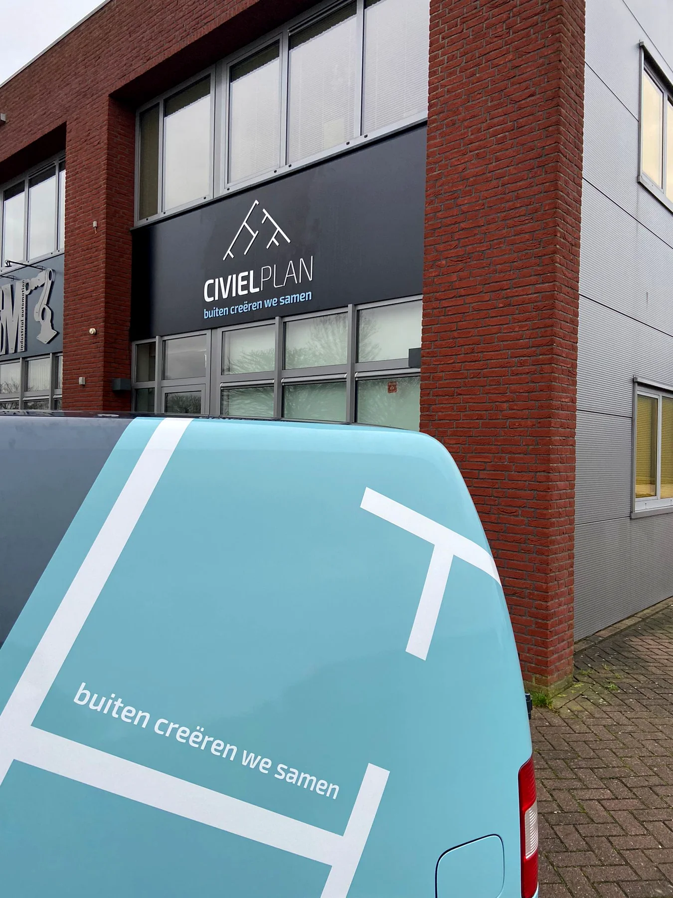 Twee Civielplan-bedrijfswagens voor het beletterde bedrijfspand
