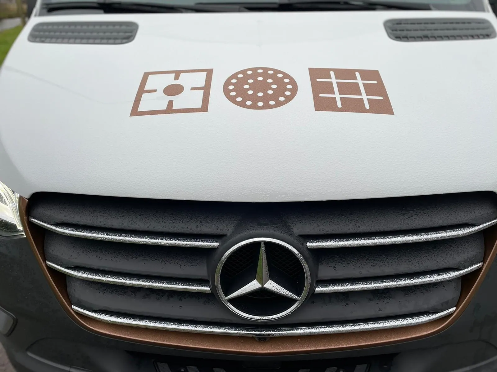 Een rijdende showroom met gedeeltelijke wrap, detail van de motorkap en de huisstijliconen.