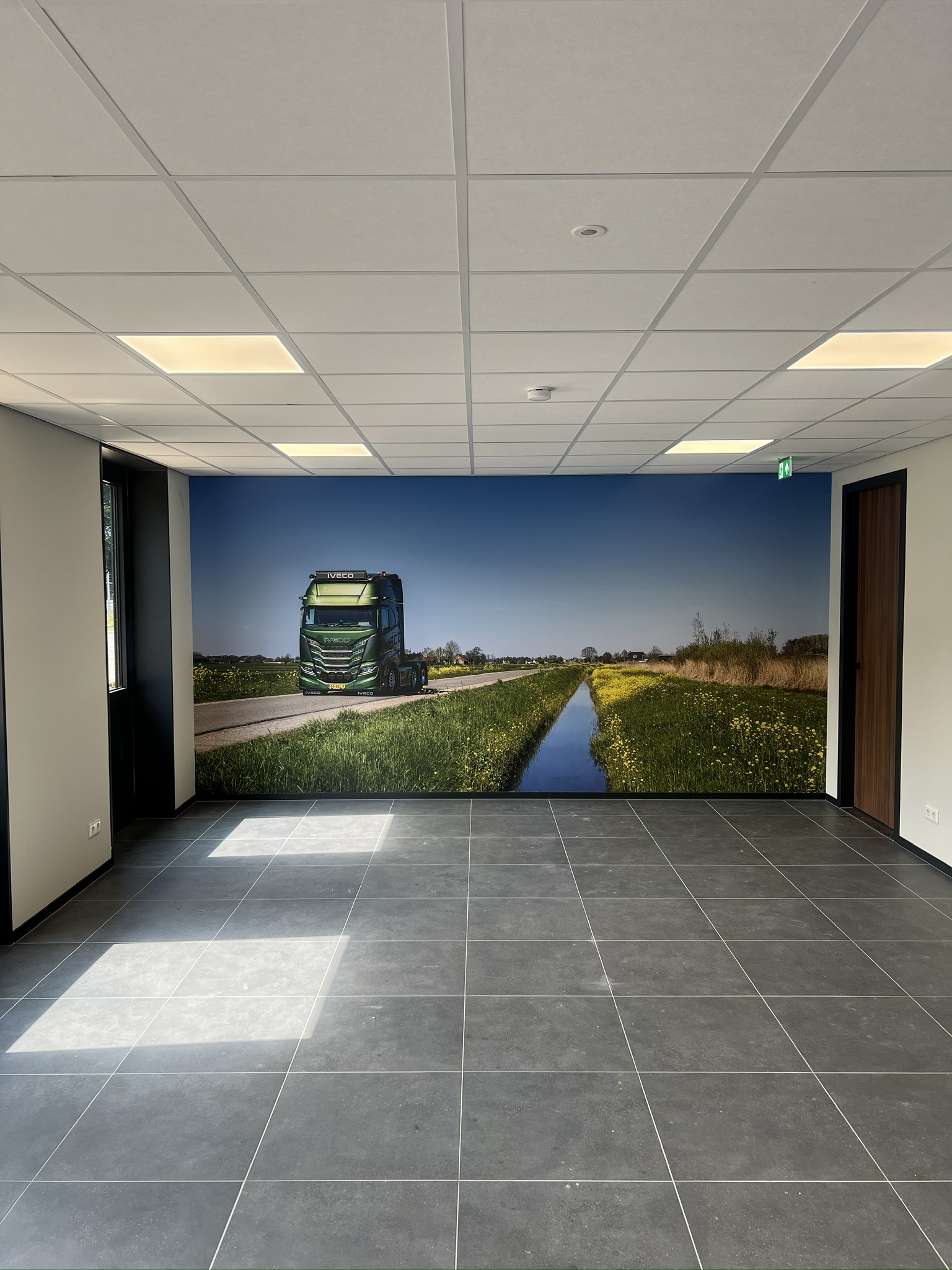 Kamerbrede fotowand met een groene Iveco in een Nederlands landschap