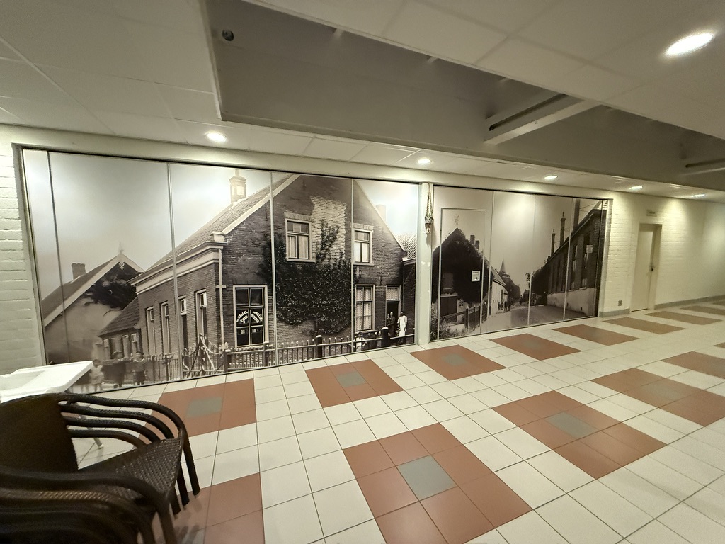 Lange historische zwart-wit fotowand over panelen en een deur