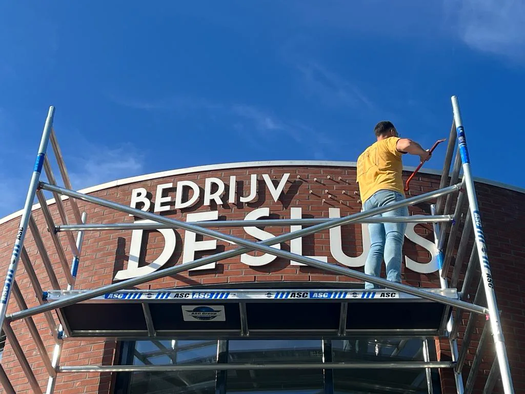 Montagespecialist van Cornelissen Reclame aan het werk aan gevelletters