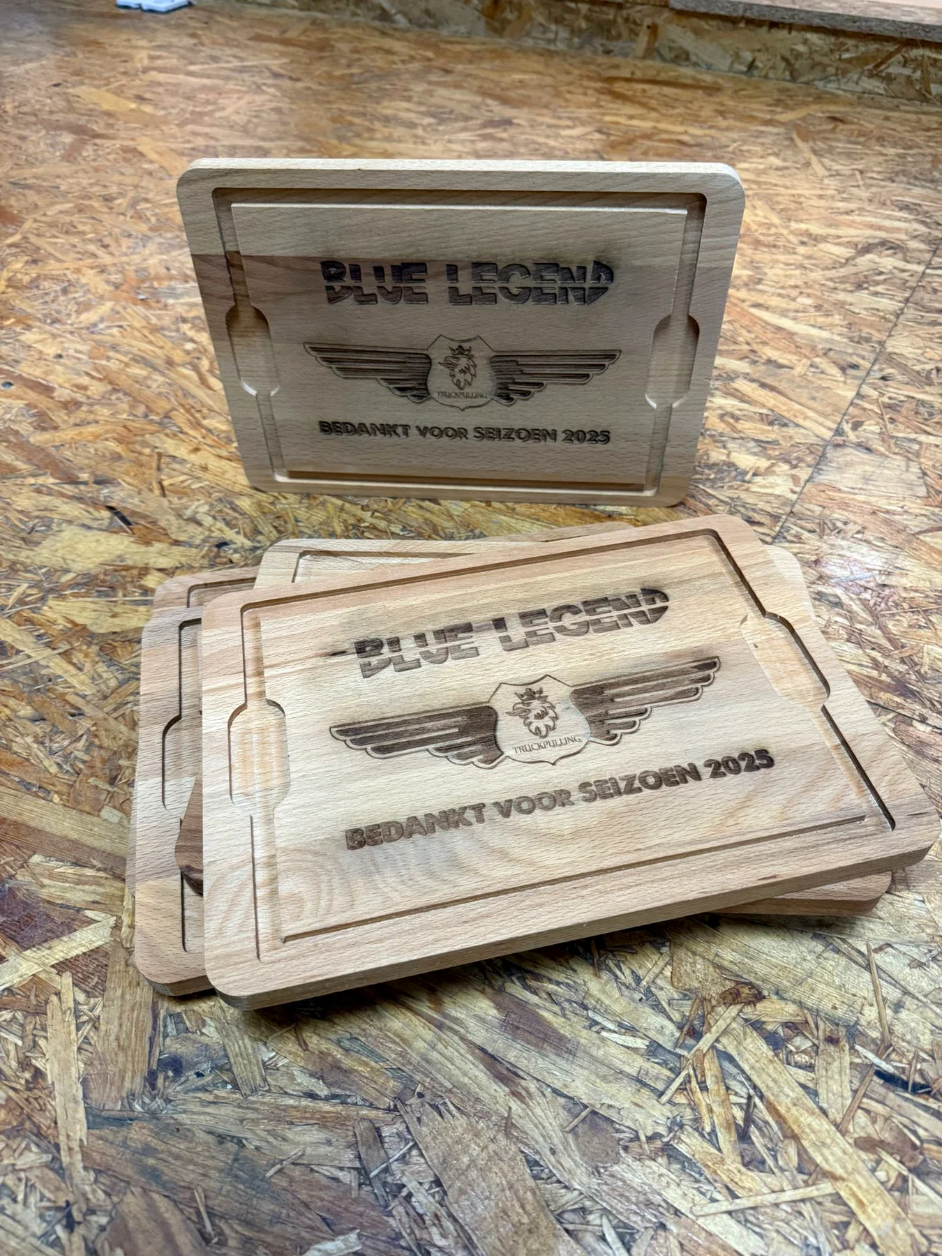 Serie identieke houten Blue Legend-bedankplanken op een werktafel