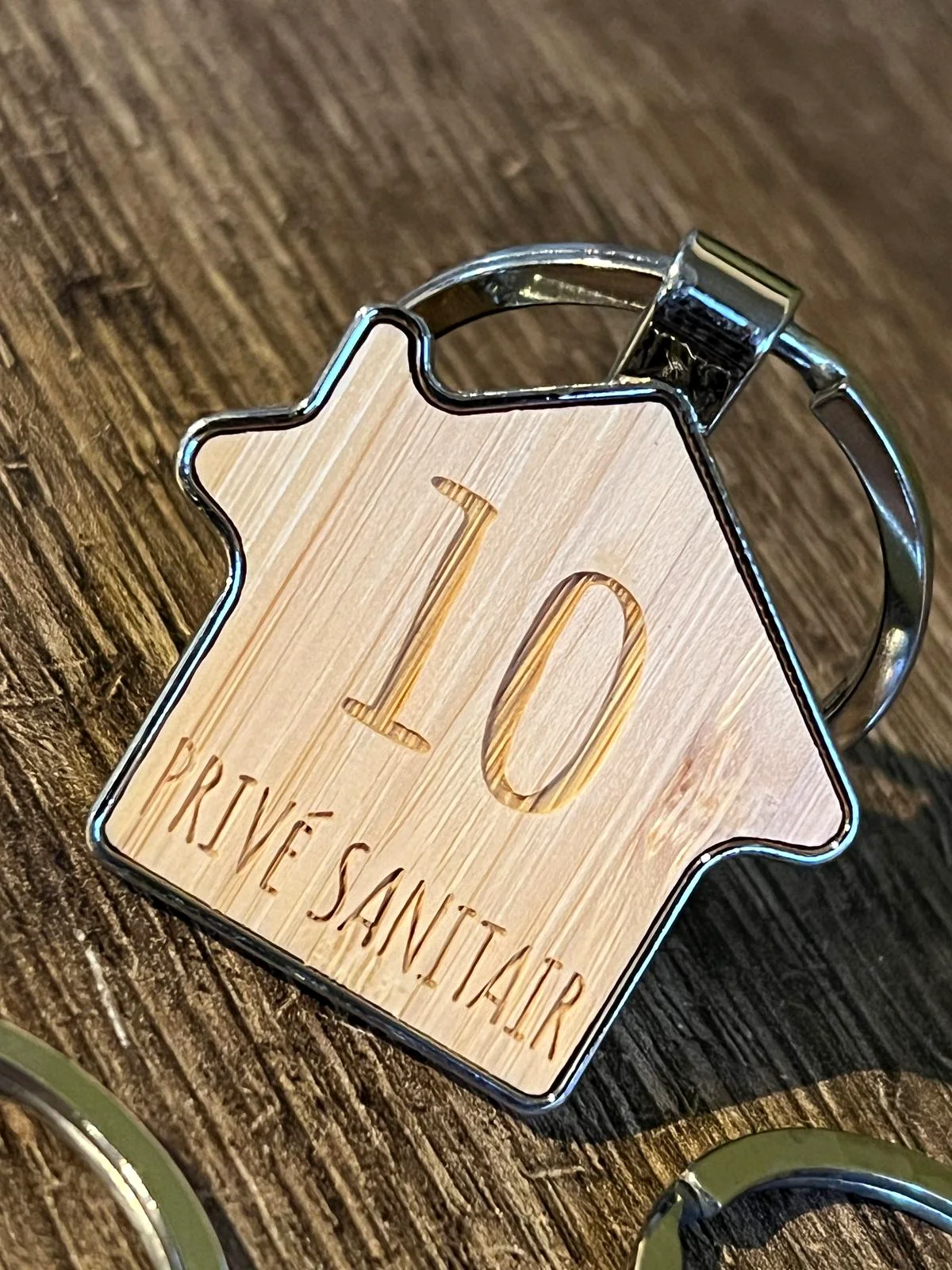 Houten huisvormige sleutelhanger met nummer 10 en de tekst Privé Sanitair
