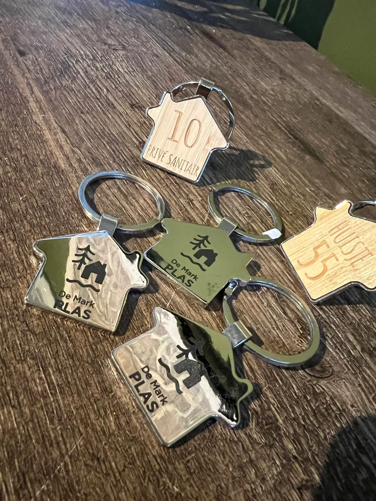 Overzicht van gegraveerde huisvormige sleutelhangers voor De Mark Plas