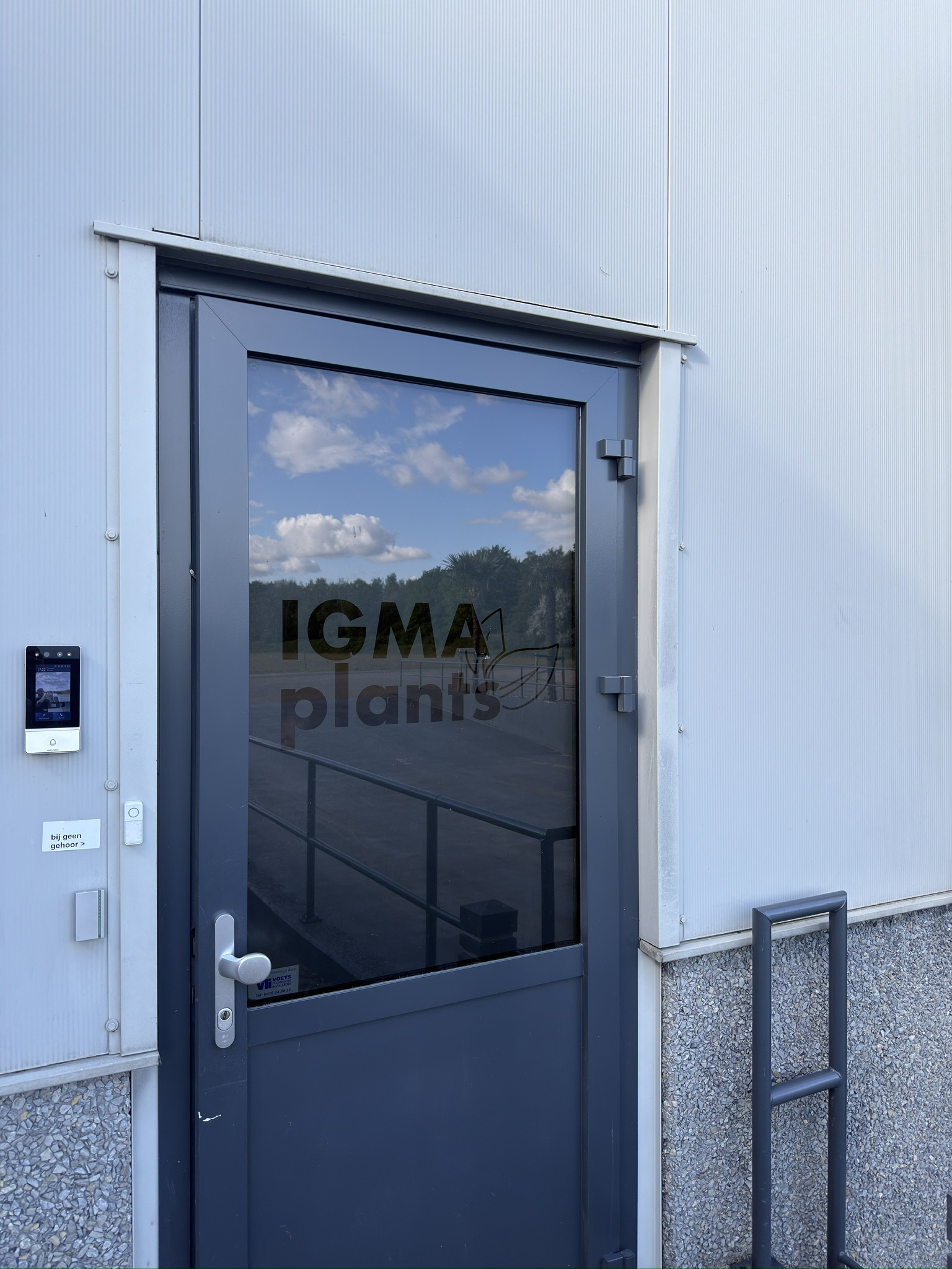 Buitendeur van IGMA Plants met donkere raambelettering op transparant glas