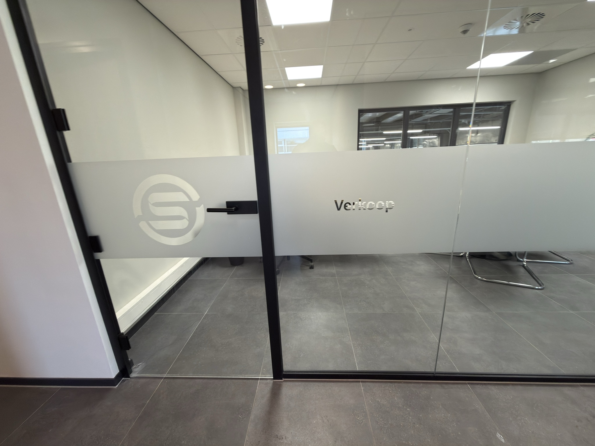 Verkoopkantoor achter een glazen wand met doorlopende dusted privacyband