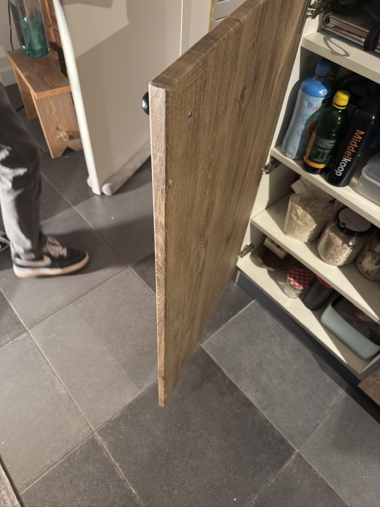Detail van de afgewerkte rand van een keukenkastdeur in houtlook