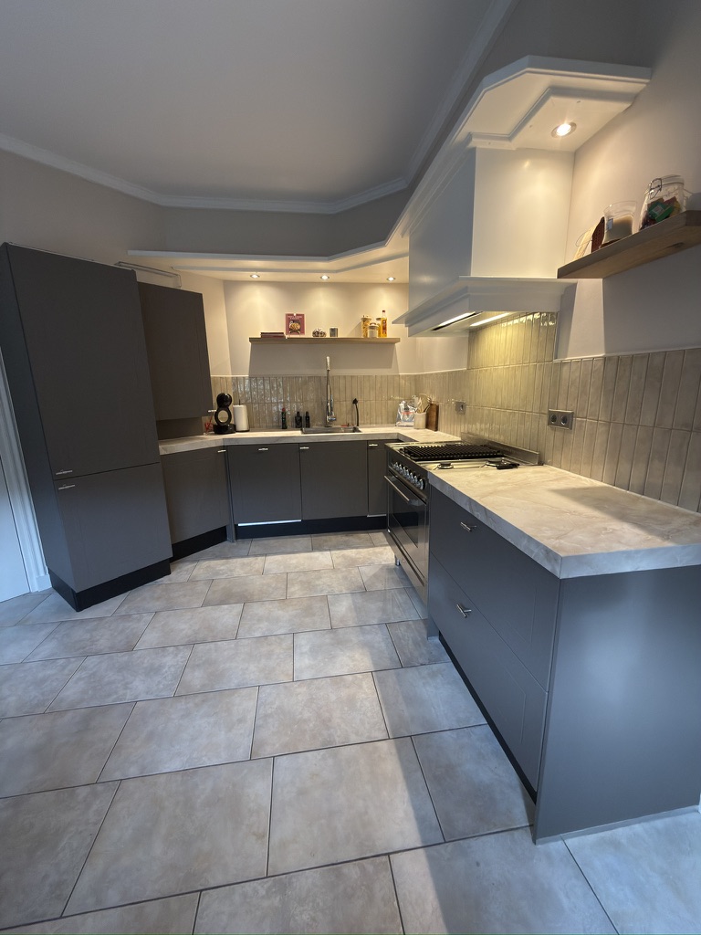 Complete keuken na herstel met grijze fronten en lichte marmerlook werkbladen