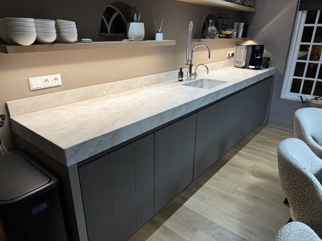Lange keukenwand met grijze houtlook fronten en marmerlook werkblad