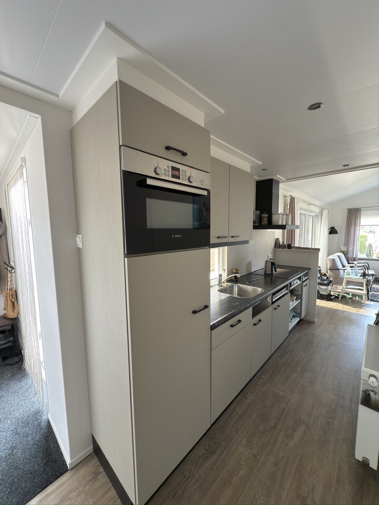 Hoge ovenkast in lichte houtlook met zwarte handgrepen