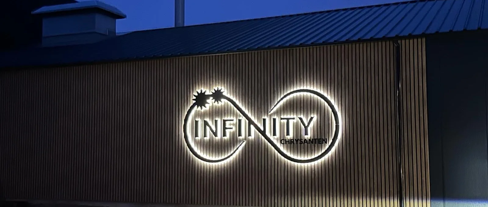 Verlichte gevelletters van Infinity Chrysanten bij avondlicht