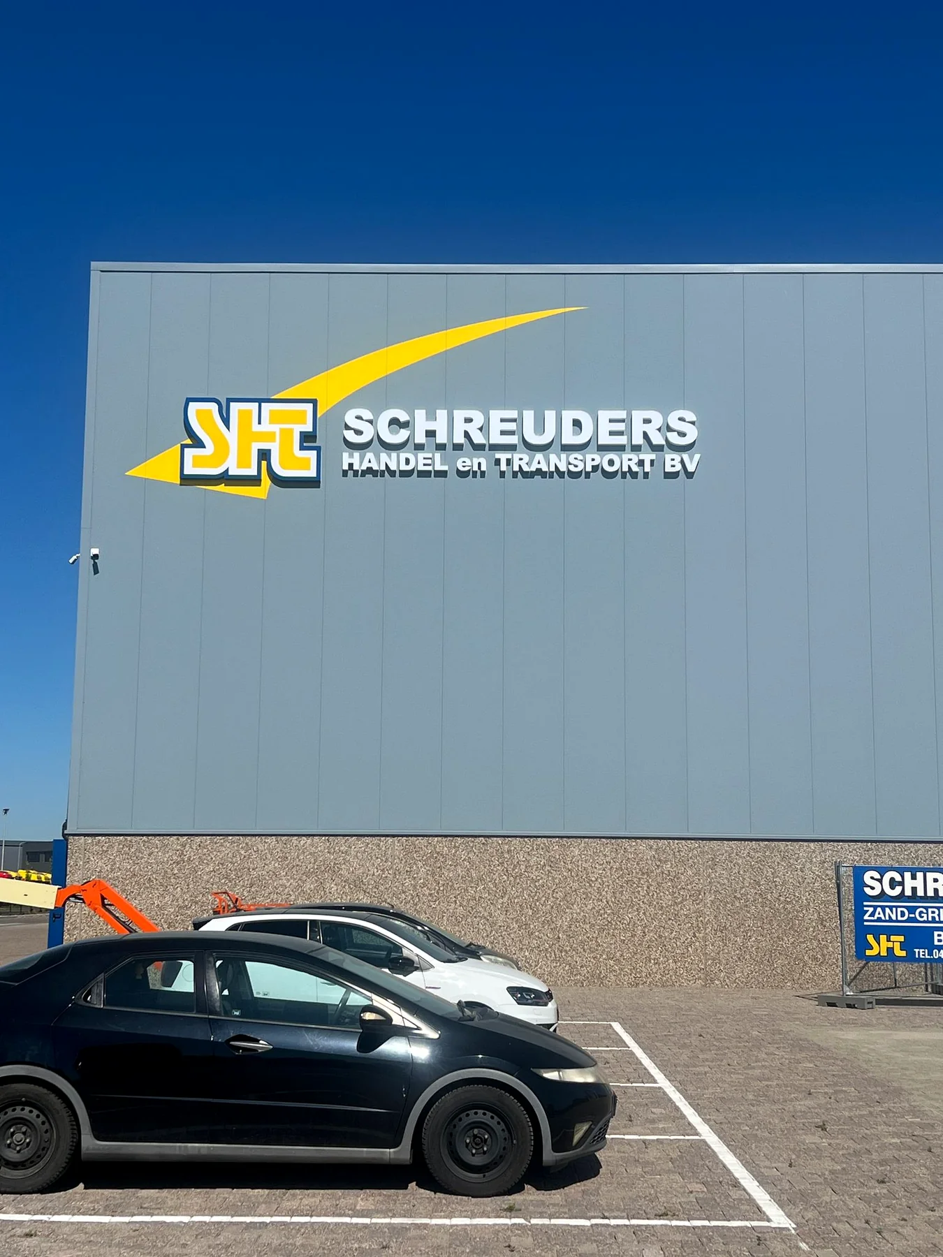 Grote gevellichtreclame voor Schreuders Handel en Transport bij daglicht