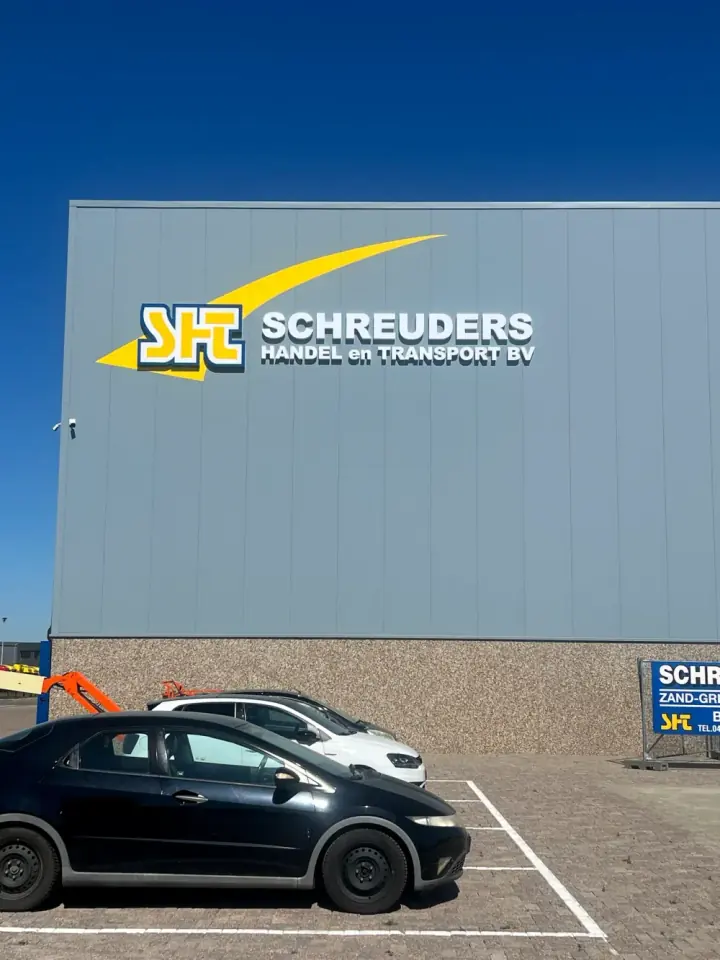 Grote gevellichtreclame voor Schreuders Handel en Transport bij daglicht