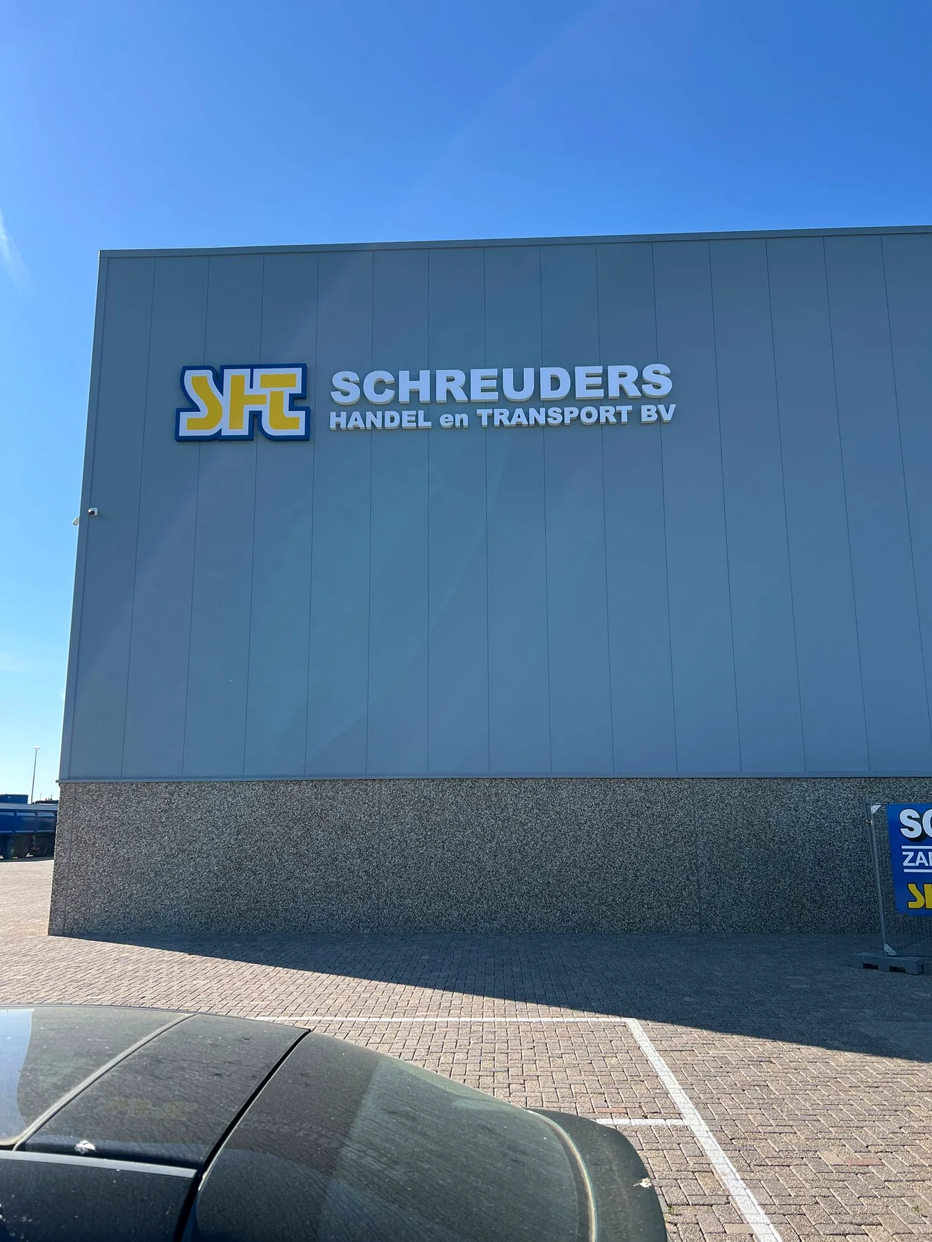 Eerste montagefase van de letters Schreuders Handel en Transport op de gevel