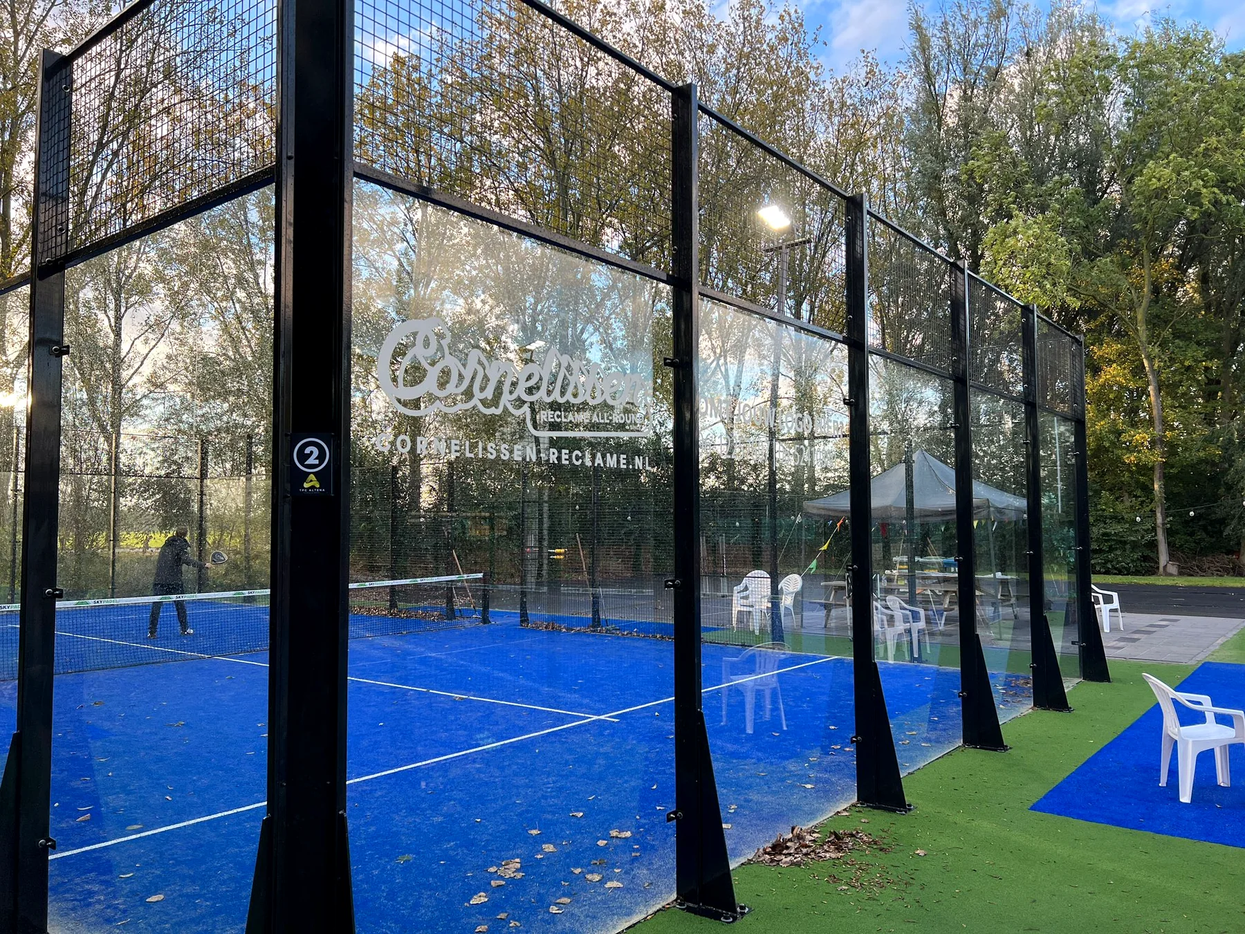 Clubreclame en sponsorstickers op de glazen wanden van een padelbaan