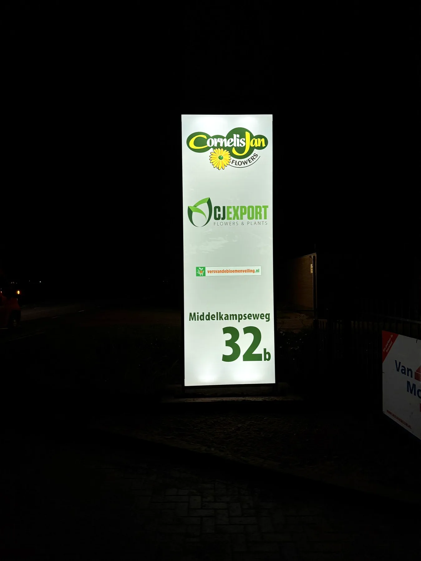 Verlichte reclamezuil van CJ Export in de avond