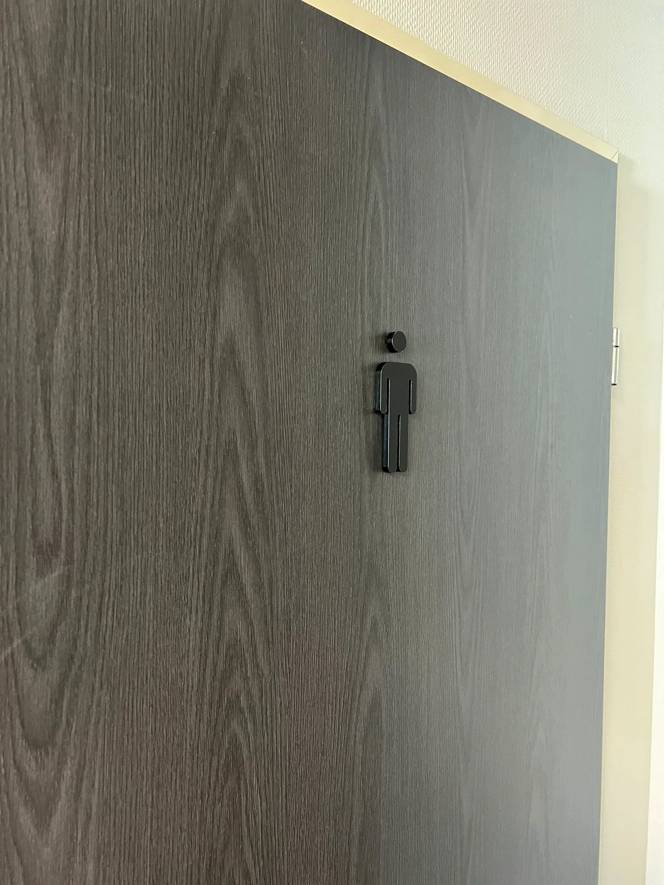 Zwart herenpictogram op een deur in donkere houtlook