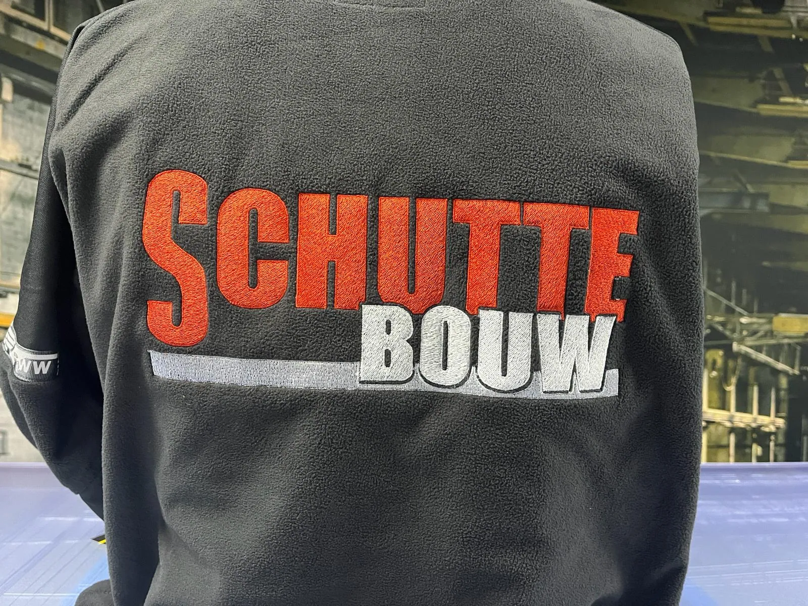 Stevige kleding voor een herkenbaar bouwteam, detail van materiaal en bedrukking.