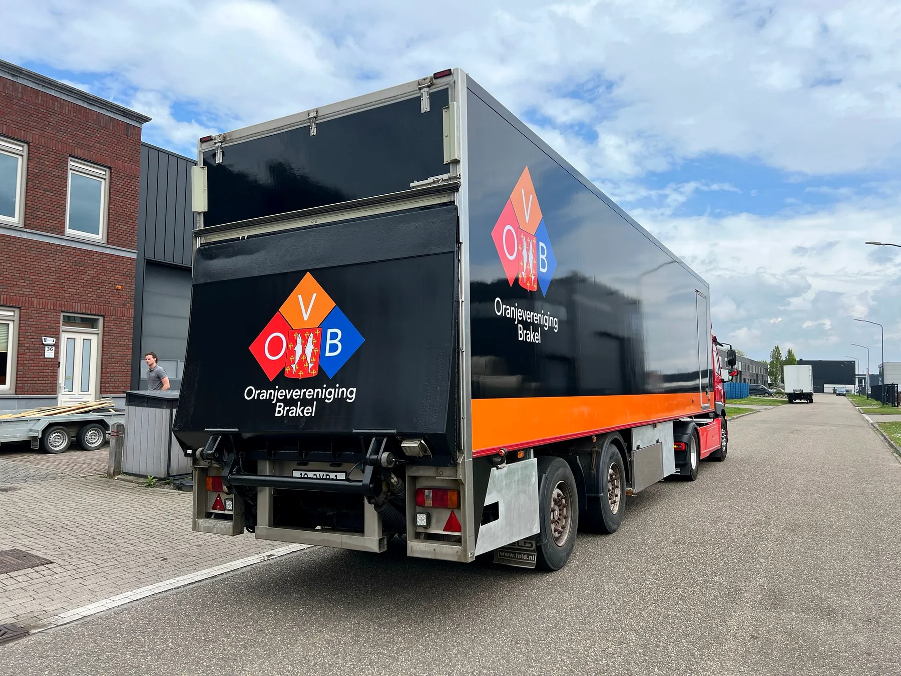 Zwart-oranje trailer met OVB-logo op de zijkant en achterklep