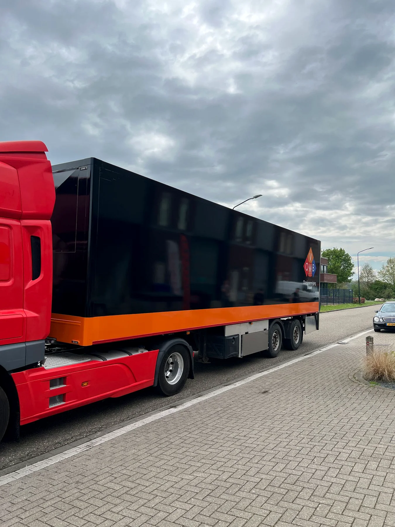Portretopname van de afgewerkte zwart-oranje trailer naast de rode vrachtwagencabine