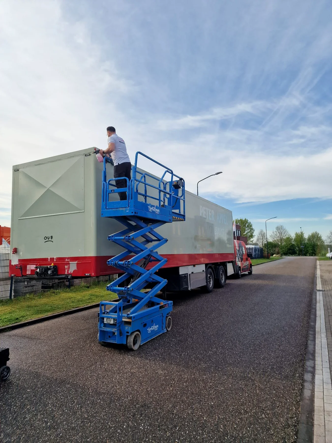 Medewerker op schaarhoogwerker tijdens de voorbereiding van de trailer