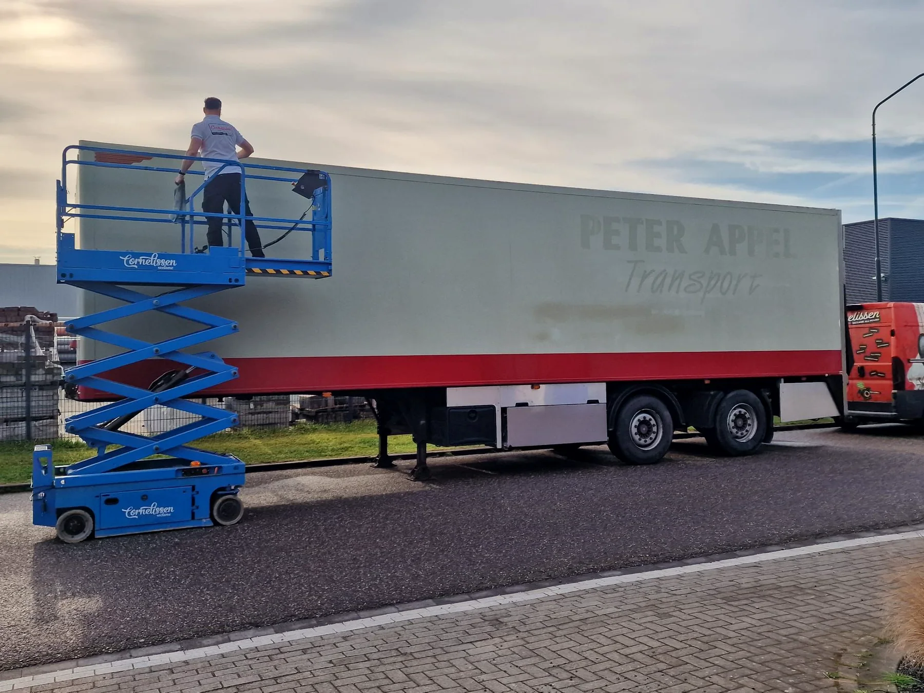 Verweerde grijs-rode transporttrailer tijdens de voorbereiding voor de wrap