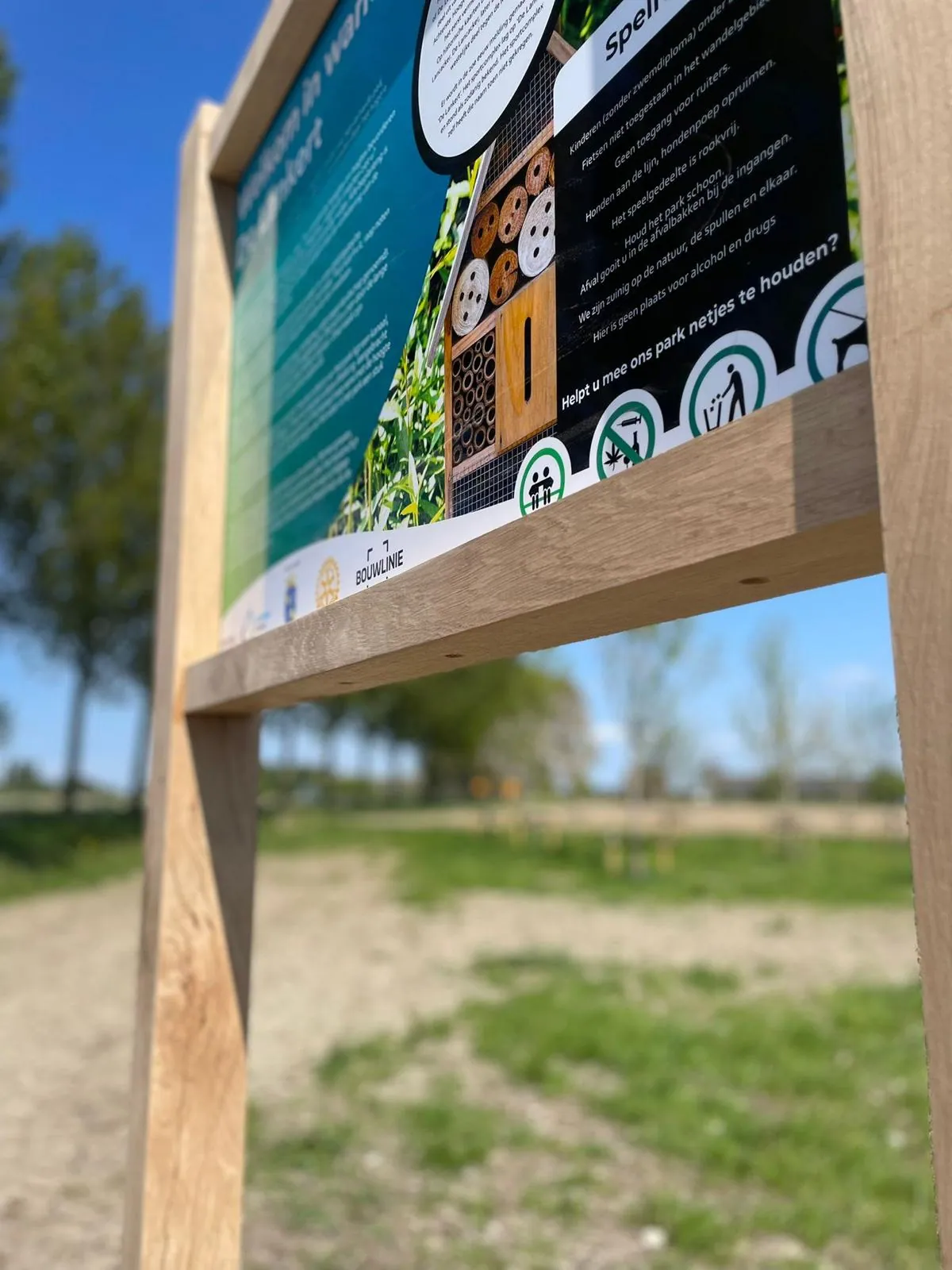 Eiken bewegwijzering die opgaat in het landschap, detail van gravure en hout.