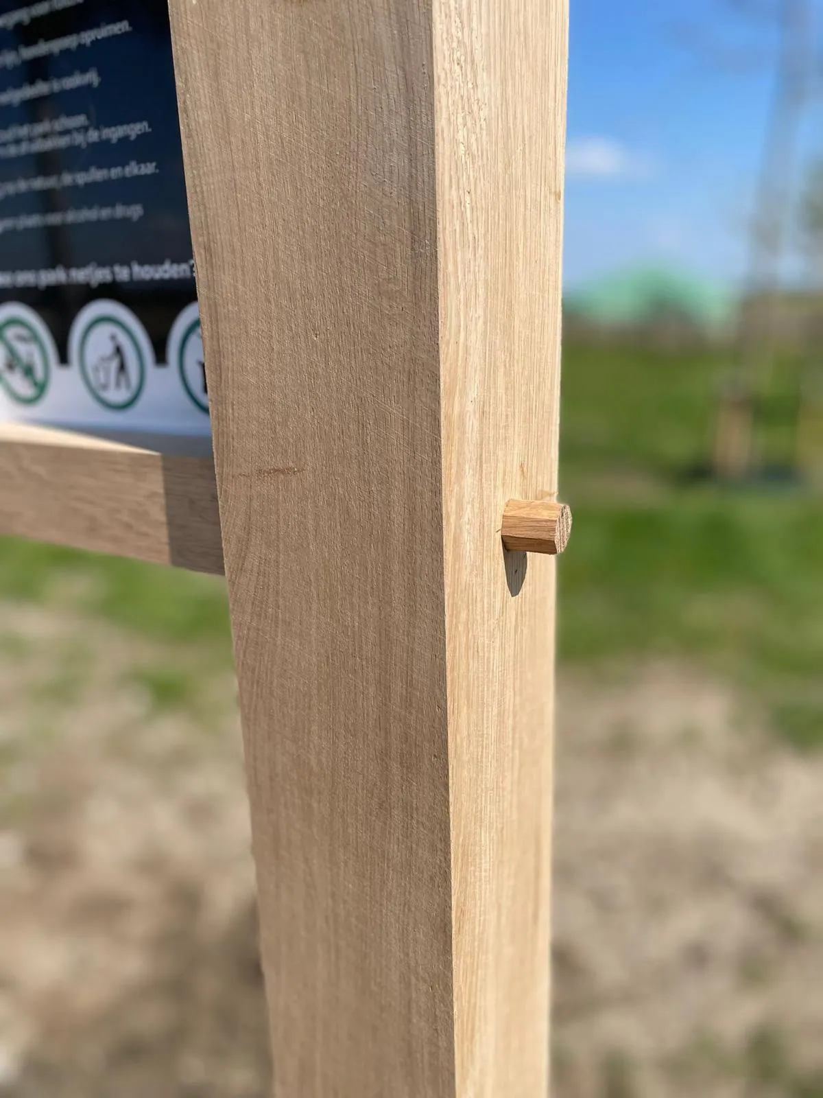 Eiken bewegwijzering die opgaat in het landschap, de paal passend in het landschap.