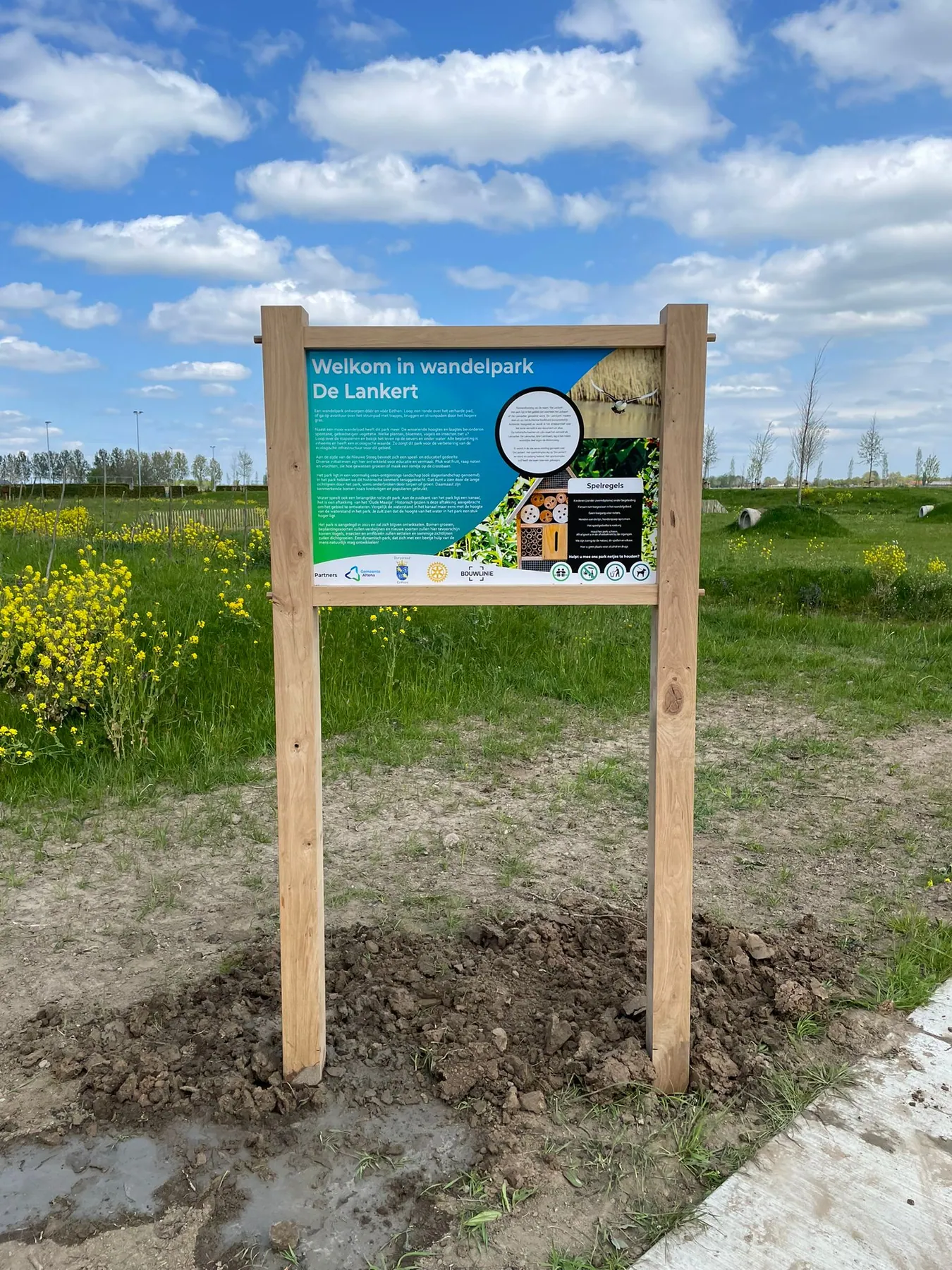 Eiken bewegwijzering die opgaat in het landschap, overzicht van het wandelgebied.